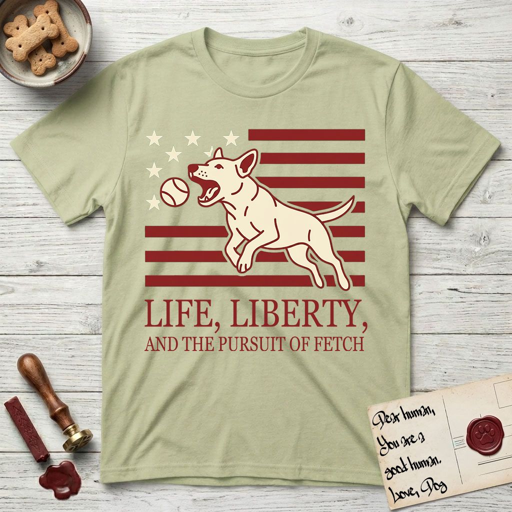 Life, Liberty, and the Pursuit of Fetch T-Shirt flat lay in Pistachio, featuring a square flag-inspired design with a Bull Terrier leaping after a ball, cream stars, and bold "Life, Liberty, and the Pursuit of Fetch" serif typography.