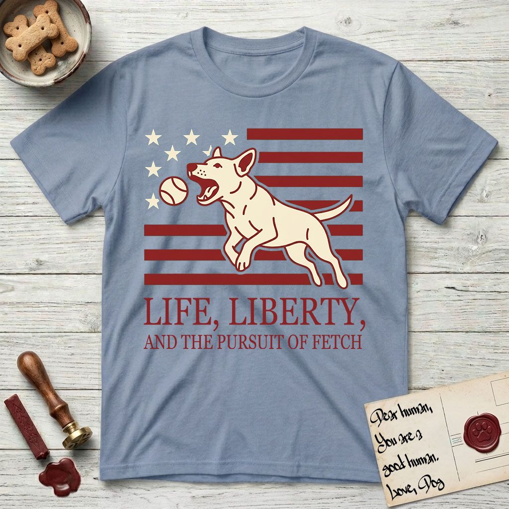 Life, Liberty, and the Pursuit of Fetch T-Shirt flat lay in Stone Blue, featuring a square flag-inspired design with a Bull Terrier leaping after a ball, cream stars, and bold "Life, Liberty, and the Pursuit of Fetch" serif typography.