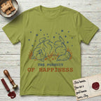 The Pursuit of Happiness T-Shirt flat lay in Kiwi, featuring a faded vintage-Americana line-art Samoyed rolling on his back in the grass with paws in the air under a sky of stars, above “The Pursuit of Happiness” lettering.