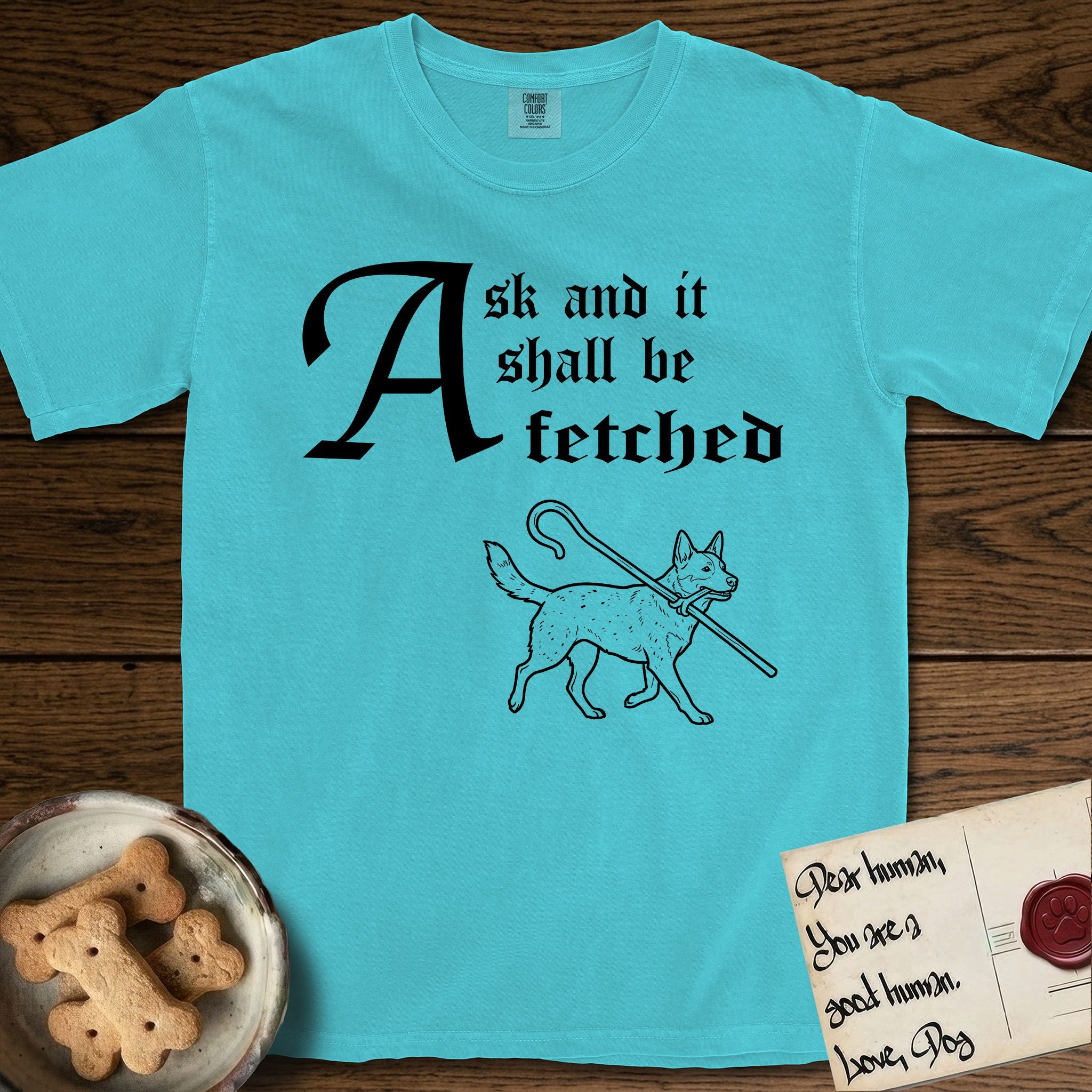 Ask and It Shall Be Fetched Australian Cattle Dog T-Shirt flat lay in Lagoon Blue, featuring a sparse pen-and-ink illustration of an Australian Cattle Dog at a proud trot carrying a shepherd's crook.