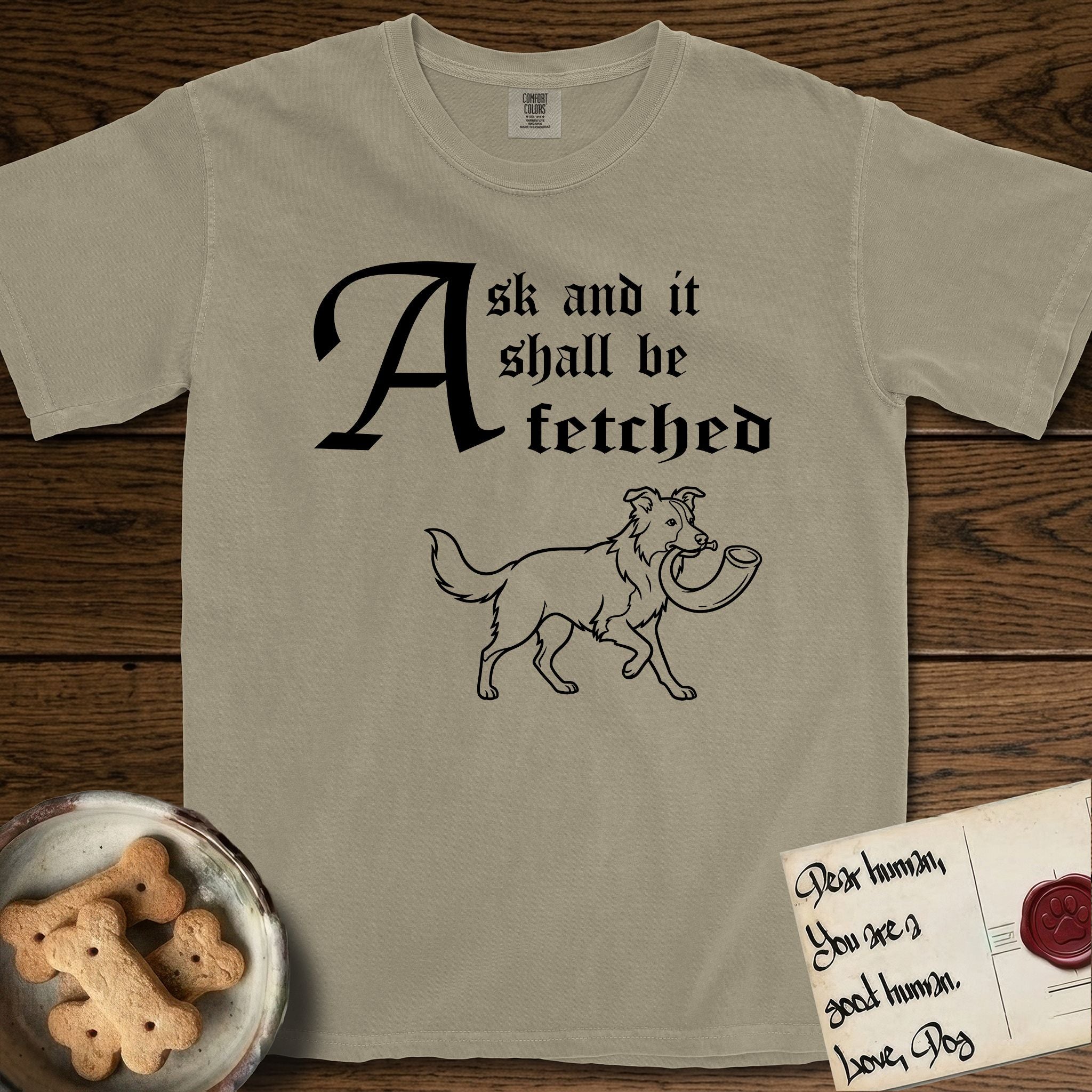 Ask and It Shall Be Fetched Border Collie T-Shirt flat lay in Khaki, featuring a sparse pen-and-ink illustration of a Border Collie at a proud trot carrying a shofar.