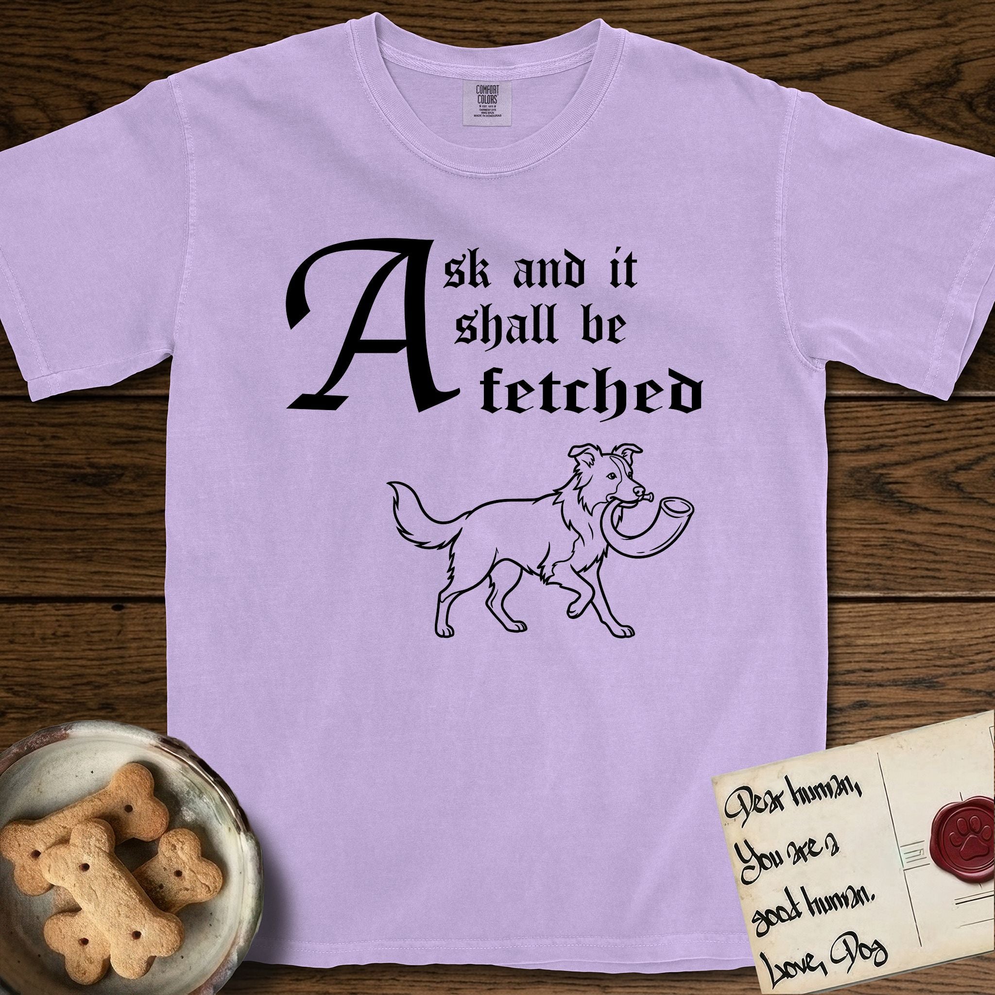 Ask and It Shall Be Fetched Border Collie T-Shirt flat lay in Orchid, featuring a sparse pen-and-ink illustration of a Border Collie at a proud trot carrying a shofar.
