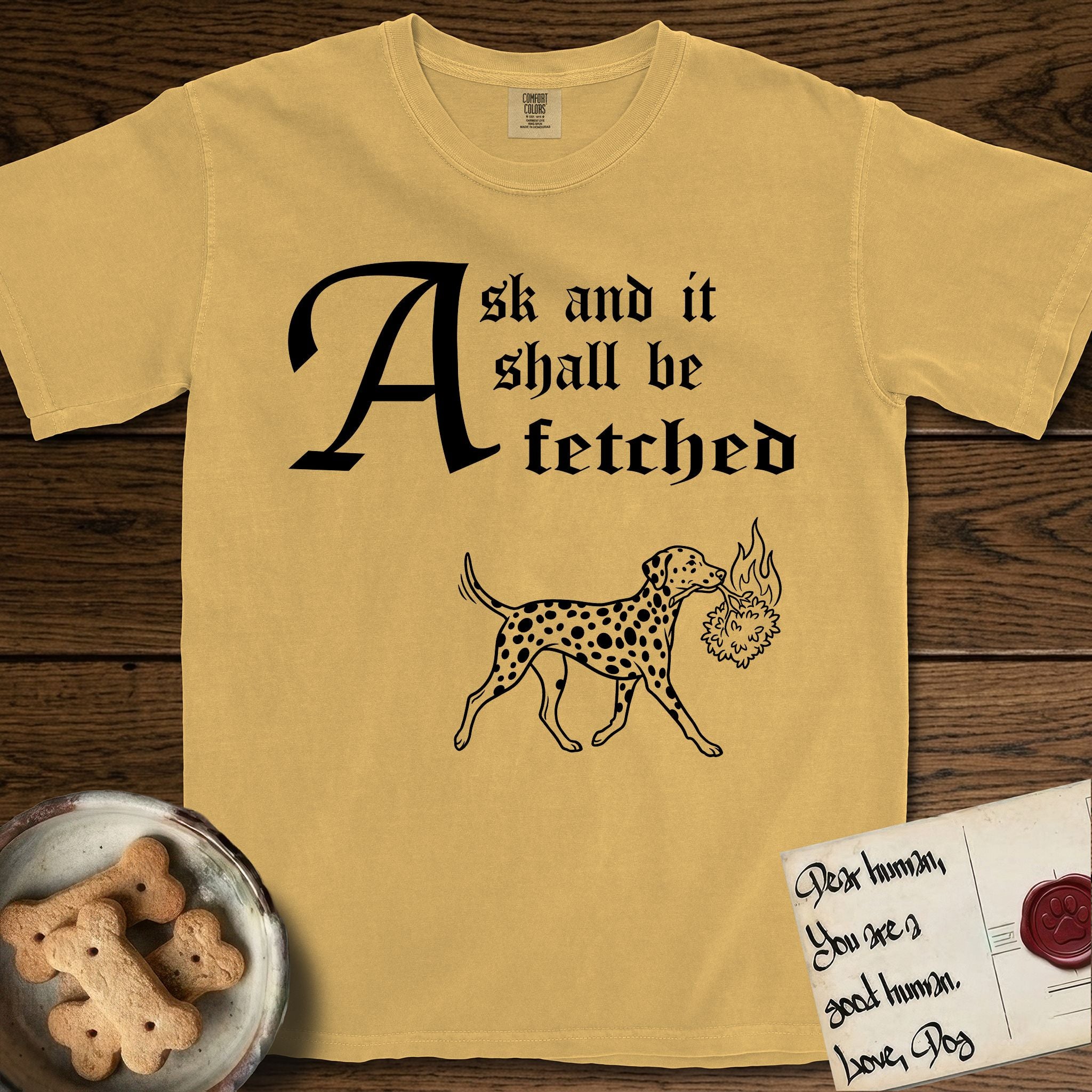 Ask and It Shall Be Fetched Dalmatian T-Shirt flat lay in Mustard, featuring a sparse pen-and-ink illustration of a Dalmatian at a proud trot carrying a small burning bush.