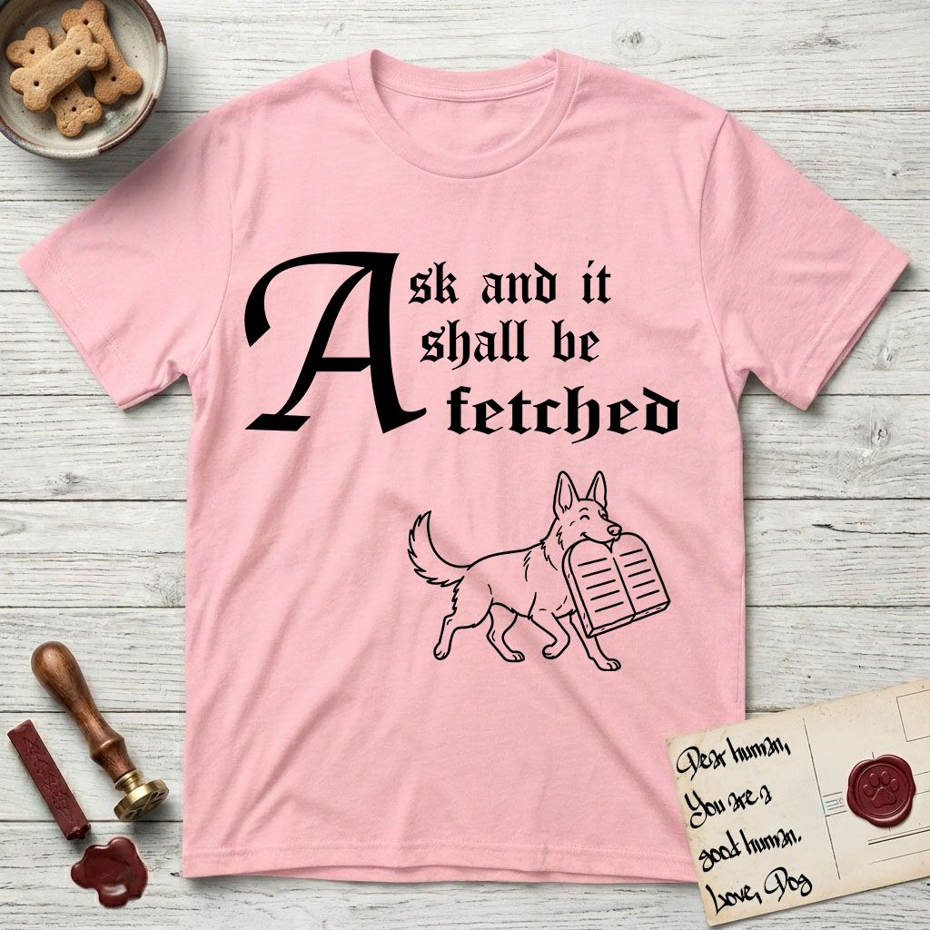 Ask and It Shall Be Fetched German Shepherd T-Shirt flat lay in Light Pink, featuring a sparse pen-and-ink illustration of a German Shepherd at a proud trot carrying a pair of stone tablets.