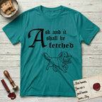 Ask and It Shall Be Fetched Golden Retriever T-Shirt flat lay in Jade Dome, featuring a sparse pen-and-ink illustration of a Golden Retriever at a proud trot carrying a golden calf idol on a plinth.
