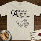 Ask and It Shall Be Fetched Newfoundland T-Shirt flat lay in Ivory, featuring a sparse pen-and-ink illustration of a Newfoundland at a proud trot carrying loaves and fishes.