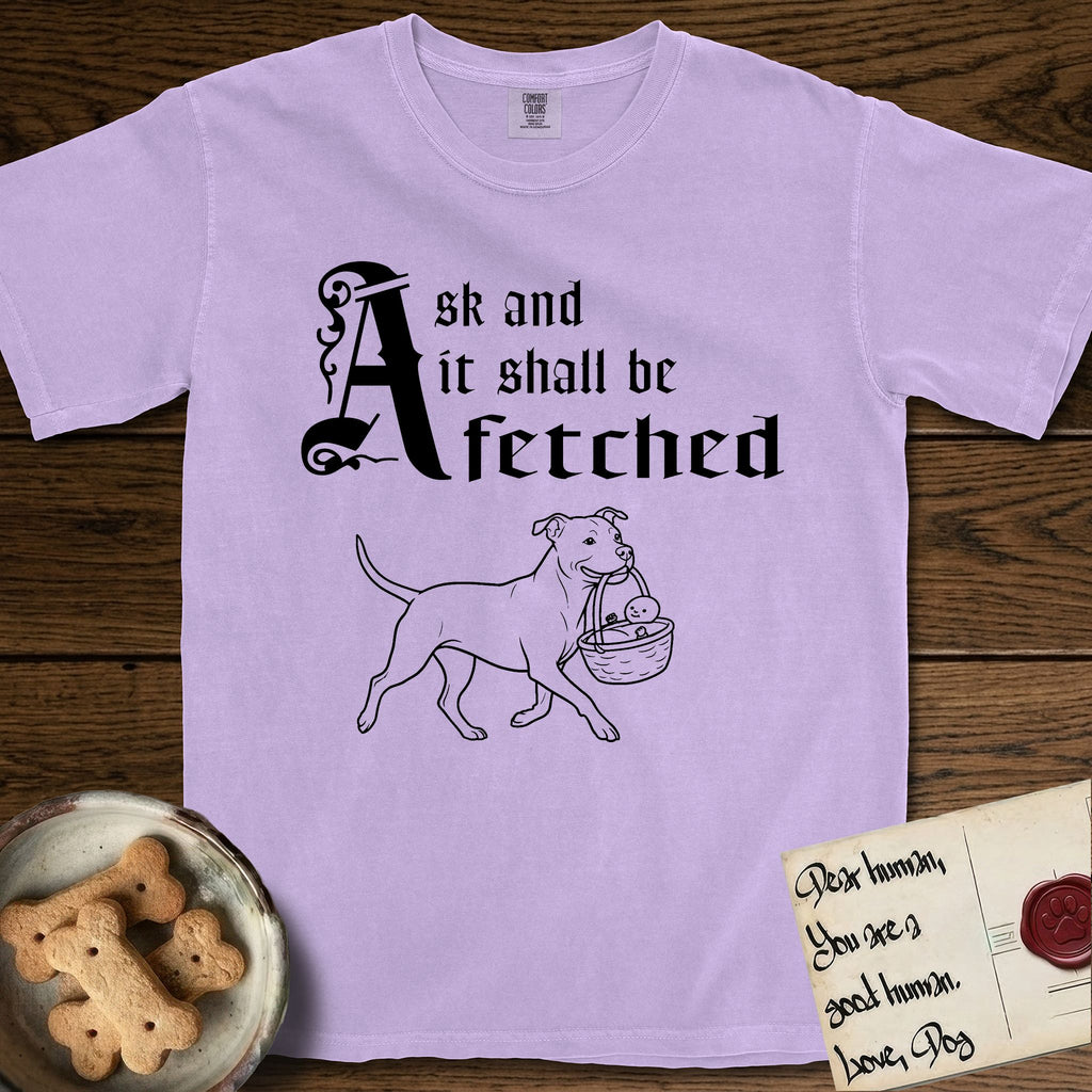 Ask and It Shall Be Fetched Pitbull T-Shirt flat lay in Orchid, featuring a sparse pen-and-ink illustration of a Pitbull at a proud trot carrying a baby in a reed basket.