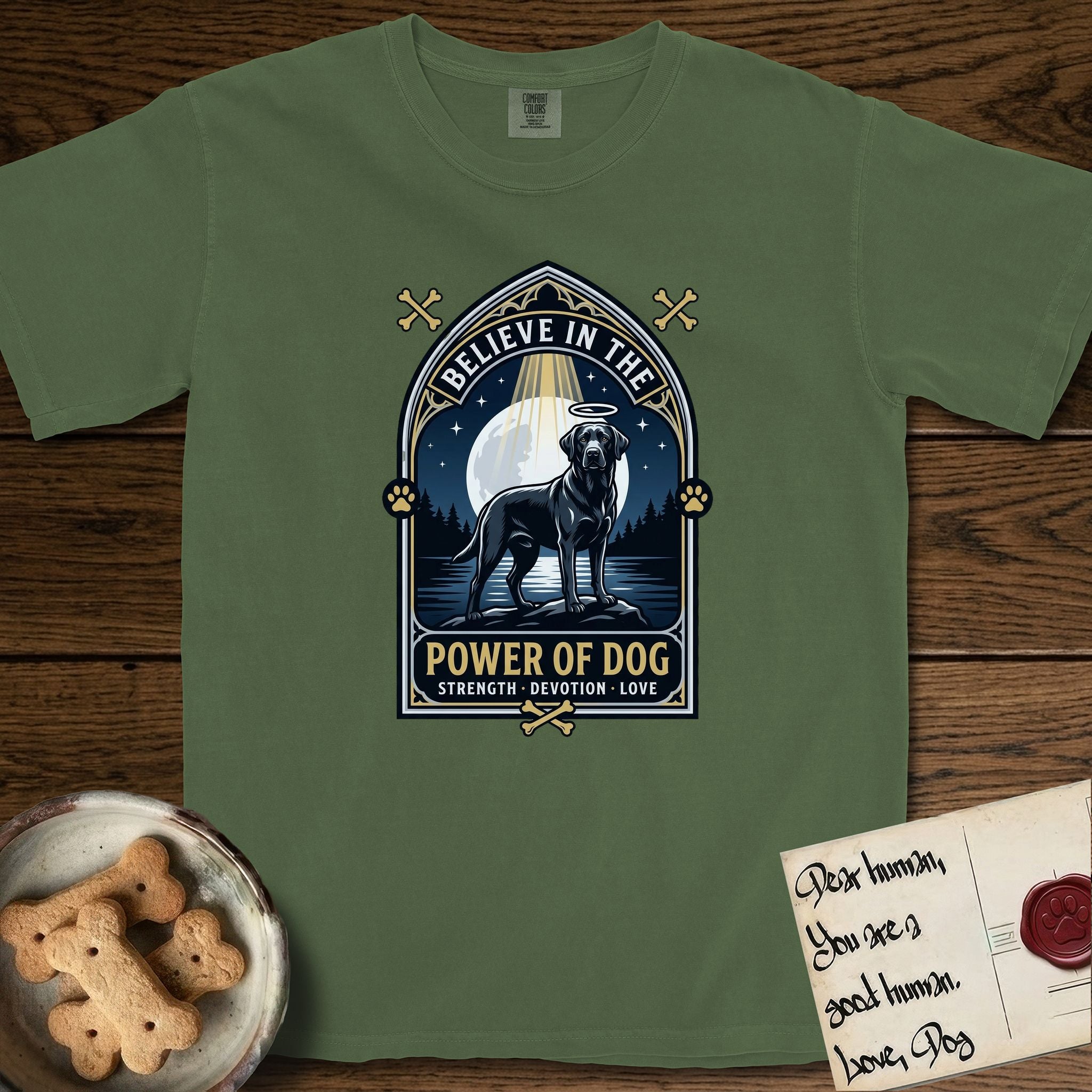 Believe in the Power of Dog Black Lab T-Shirt flat lay in Moss, featuring a dramatic gothic-arch badge with a moonlit Black Lab on a rock above still water, a beam of light through the arch, and the words Strength, Devotion, Love.