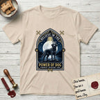 Believe in the Power of Dog Black Lab T-Shirt flat lay in Sand, featuring a dramatic gothic-arch badge with a moonlit Black Lab on a rock above still water, a beam of light through the arch, and the words Strength, Devotion, Love.