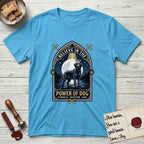 Believe in the Power of Dog Black Lab T-Shirt flat lay in Sky, featuring a dramatic gothic-arch badge with a moonlit Black Lab on a rock above still water, a beam of light through the arch, and the words Strength, Devotion, Love.