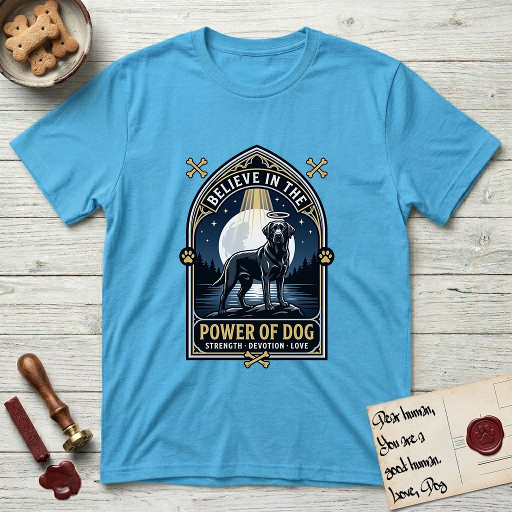 Believe in the Power of Dog Black Lab T-Shirt flat lay in Sky, featuring a dramatic gothic-arch badge with a moonlit Black Lab on a rock above still water, a beam of light through the arch, and the words Strength, Devotion, Love.