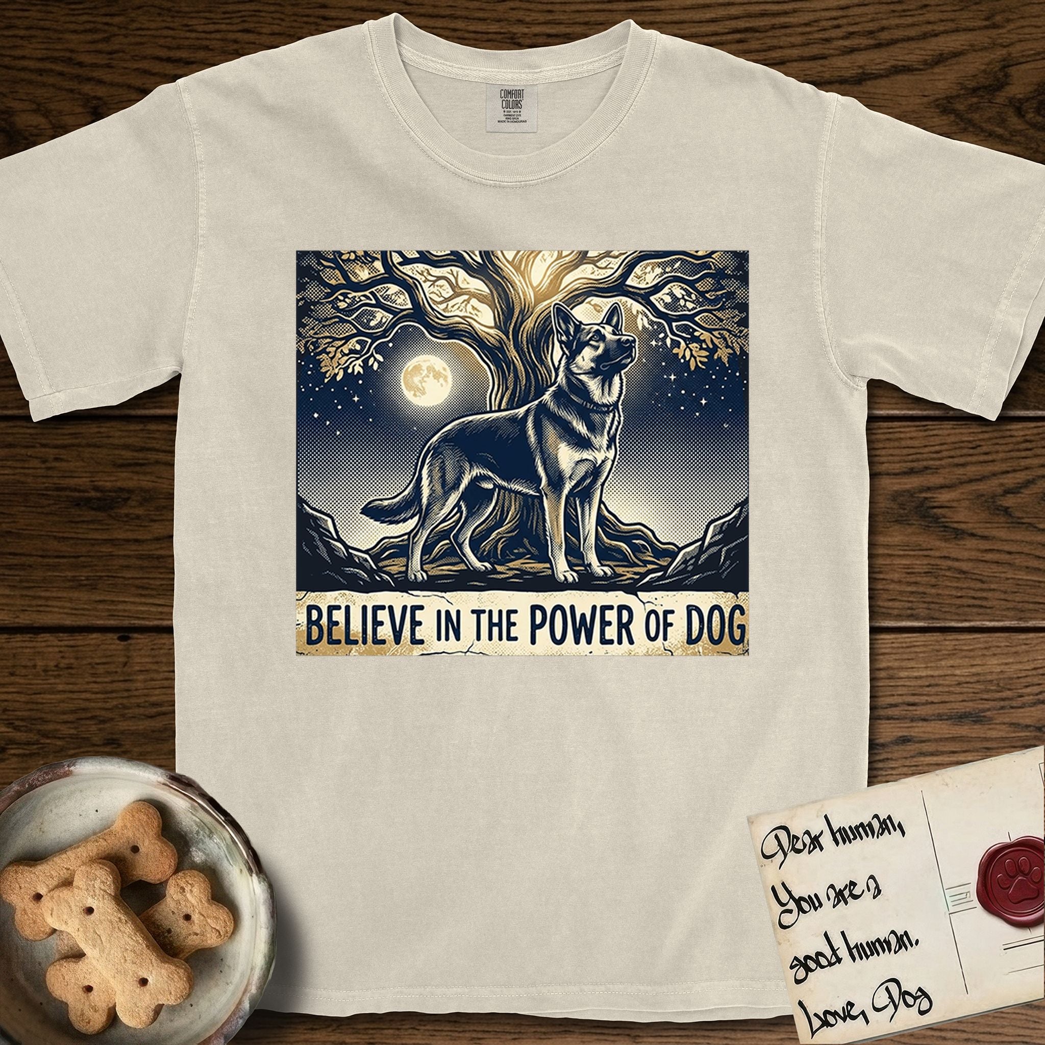 Believe in the Power of Dog German Shepherd T-Shirt flat lay in Ivory, featuring a moonlit illustration of a German Shepherd standing beneath a great tree whose roots and branches reach equally in both directions.
