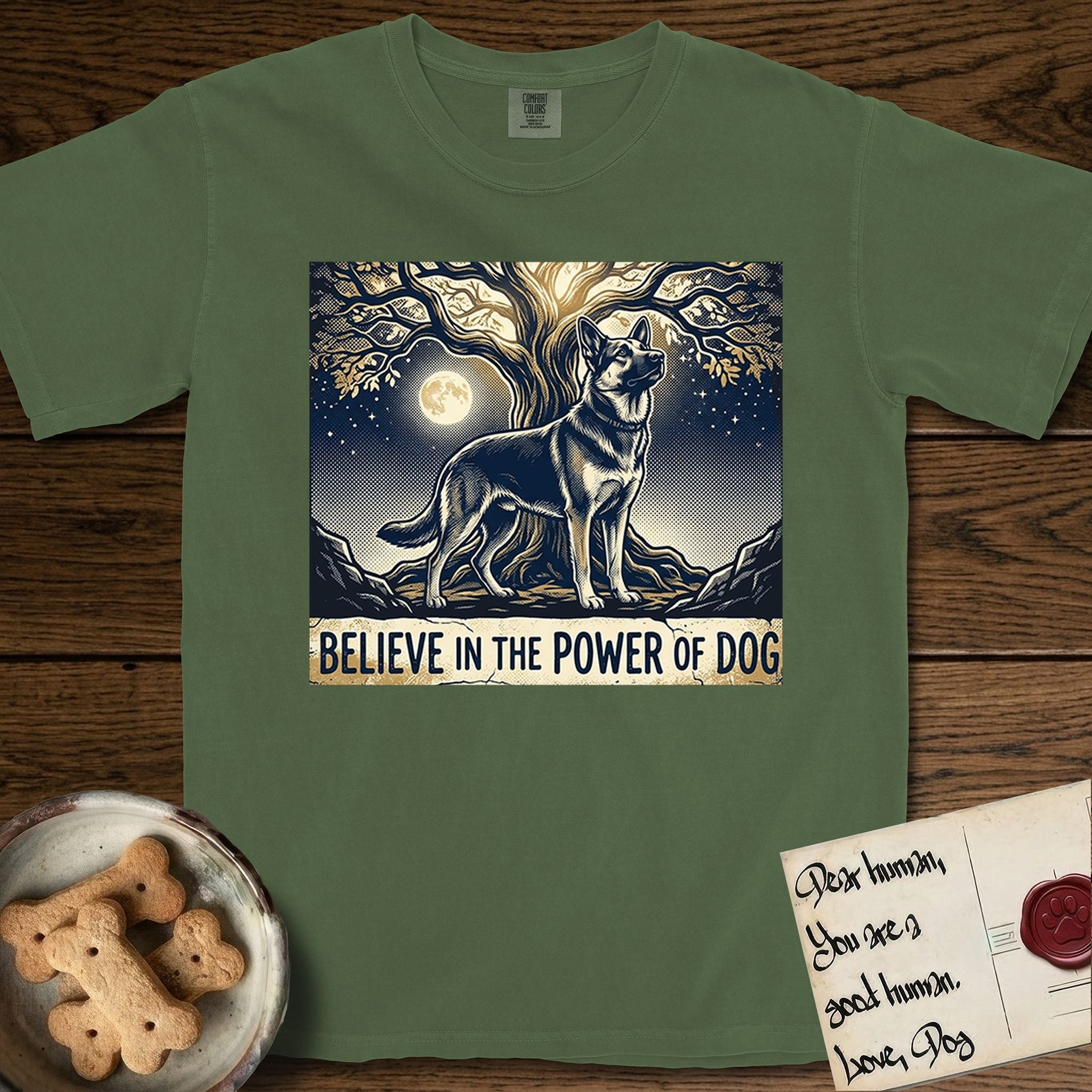 Believe in the Power of Dog German Shepherd T-Shirt flat lay in Moss, featuring a moonlit illustration of a German Shepherd standing beneath a great tree whose roots and branches reach equally in both directions.