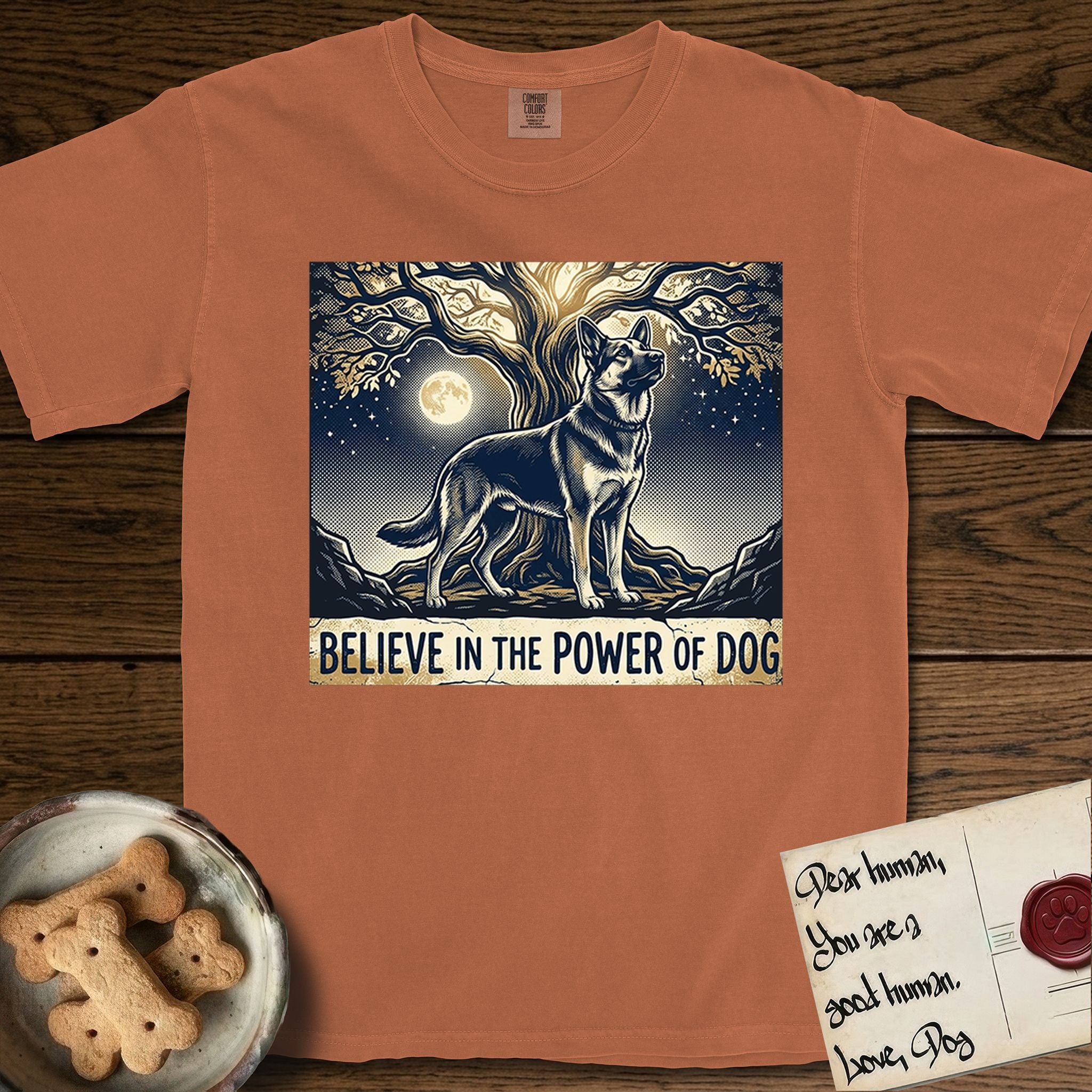 Believe in the Power of Dog German Shepherd T-Shirt flat lay in Yam, featuring a moonlit illustration of a German Shepherd standing beneath a great tree whose roots and branches reach equally in both directions.