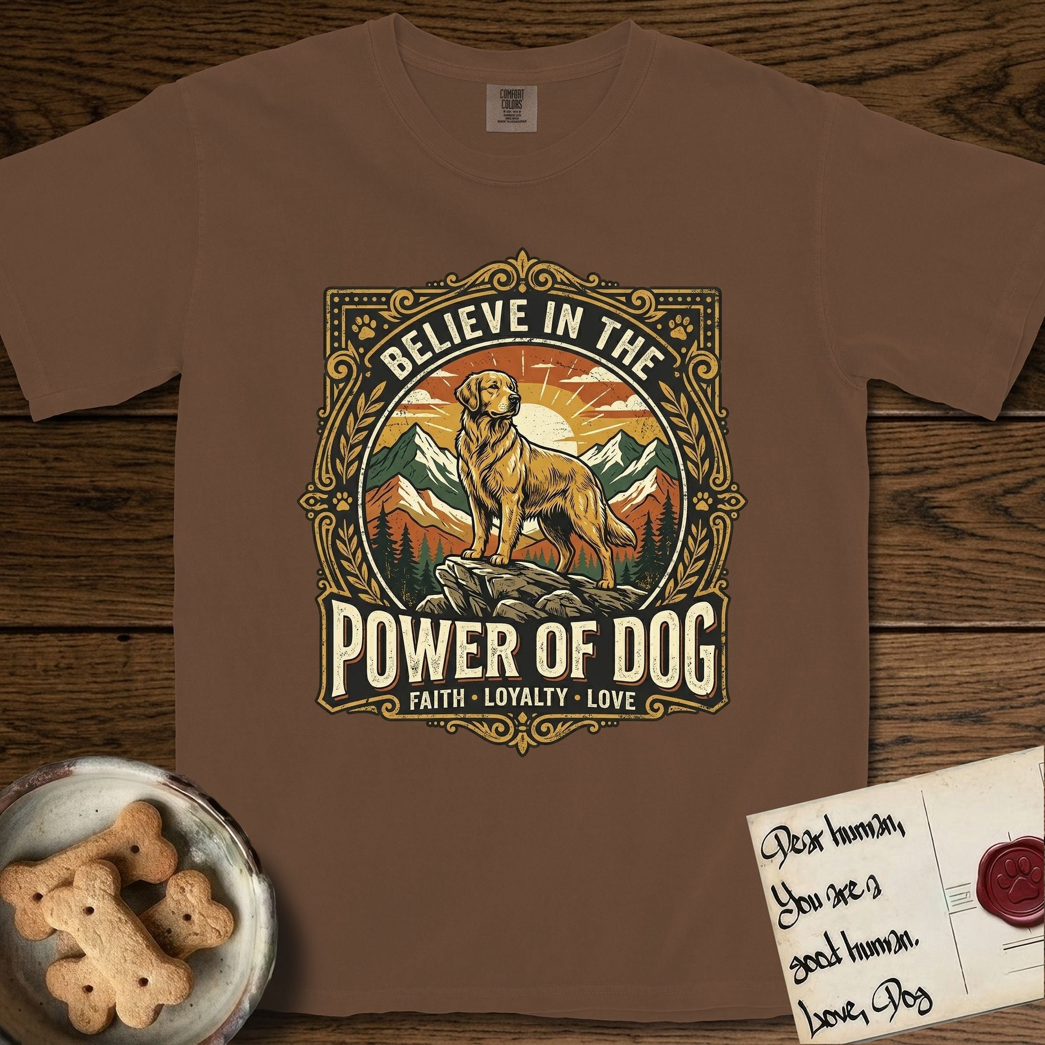 Believe in the Power of Dog Golden Retriever T-Shirt flat lay in Espresso, featuring a vintage outdoor badge with a haloed Golden Retriever standing on a rock above the treeline at sunrise and the words Faith, Loyalty, Love.