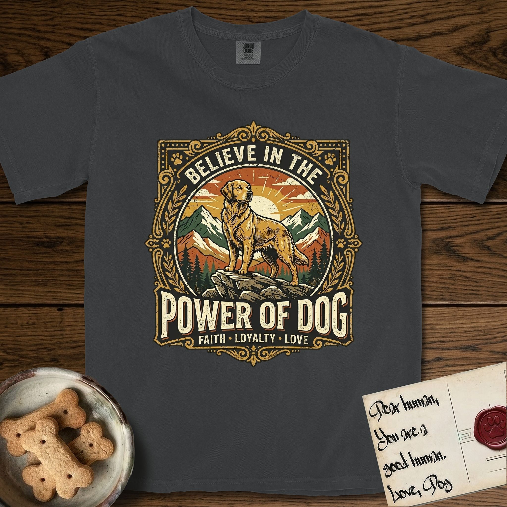 Believe in the Power of Dog Golden Retriever T-Shirt flat lay in Graphite, featuring a vintage outdoor badge with a haloed Golden Retriever standing on a rock above the treeline at sunrise and the words Faith, Loyalty, Love.
