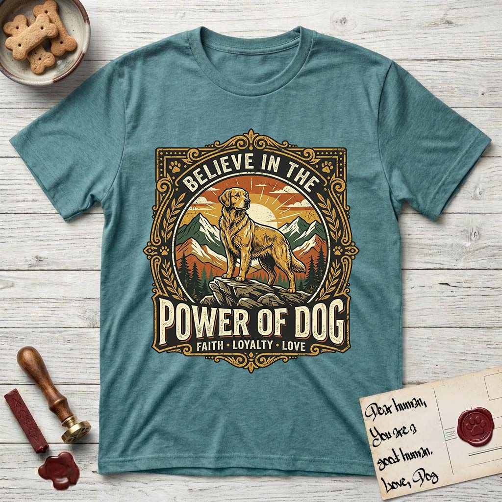 Believe in the Power of Dog Golden Retriever T-Shirt flat lay in Heather Galapagos Blue, featuring a vintage outdoor badge with a haloed Golden Retriever standing on a rock above the treeline at sunrise and the words Faith, Loyalty, Love.