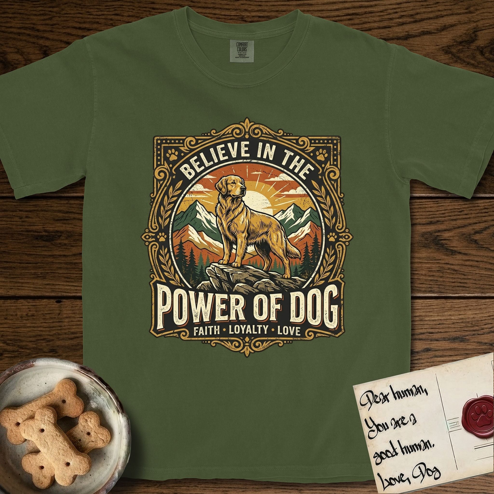 Believe in the Power of Dog Golden Retriever T-Shirt flat lay in Hemp, featuring a vintage outdoor badge with a haloed Golden Retriever standing on a rock above the treeline at sunrise and the words Faith, Loyalty, Love.