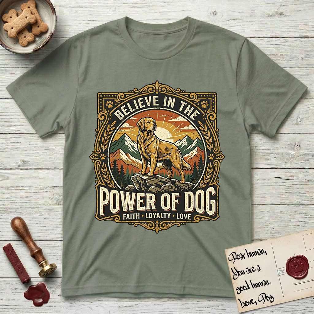 Believe in the Power of Dog Golden Retriever T-Shirt flat lay in Sage, featuring a vintage outdoor badge with a haloed Golden Retriever standing on a rock above the treeline at sunrise and the words Faith, Loyalty, Love.
