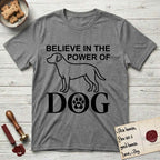 Believe in the Power of Dog Labrador T-Shirt flat lay in Graphite Heather, featuring stark minimalist single-line art of a Labrador with bold stacked "Believe in the Power of Dog" type and a paw-print heart in the O.