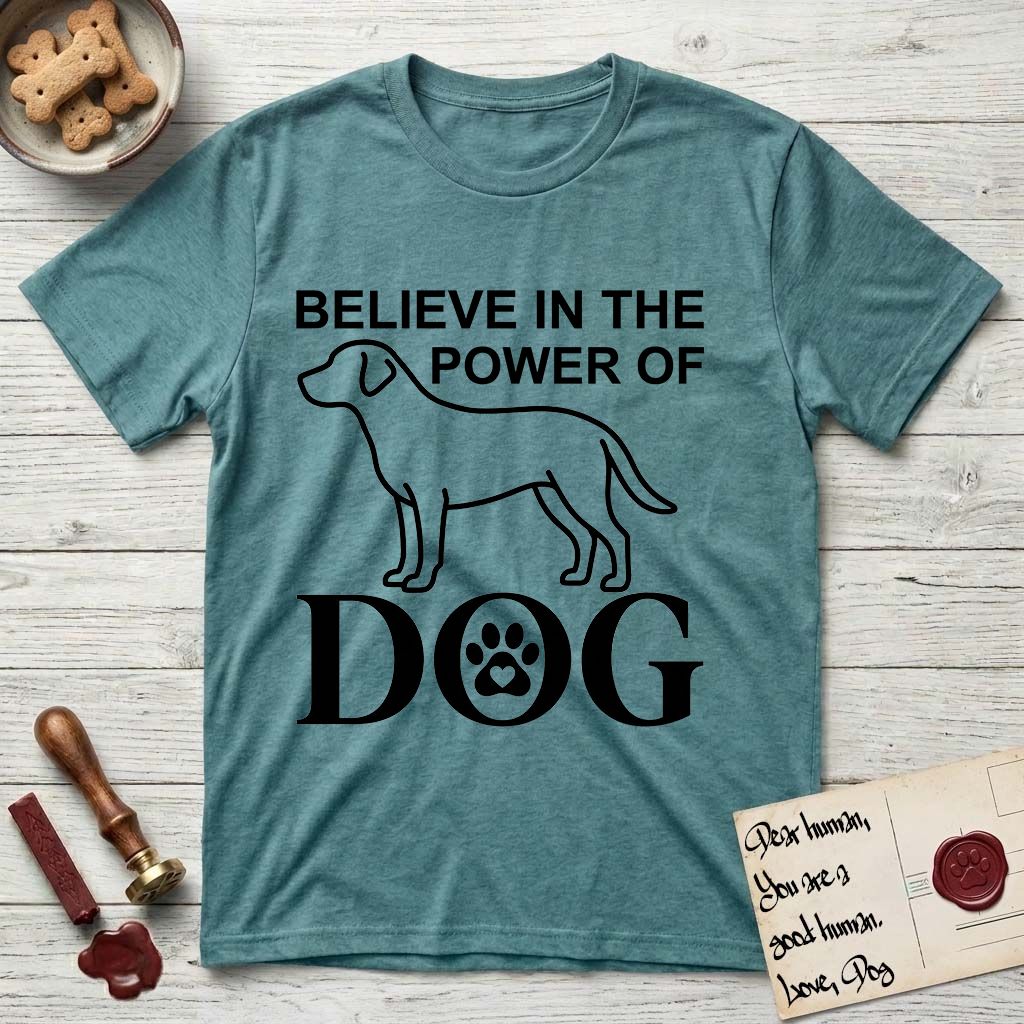 Believe in the Power of Dog Labrador T-Shirt flat lay in Heather Galapagos Blue, featuring stark minimalist single-line art of a Labrador with bold stacked "Believe in the Power of Dog" type and a paw-print heart in the O.