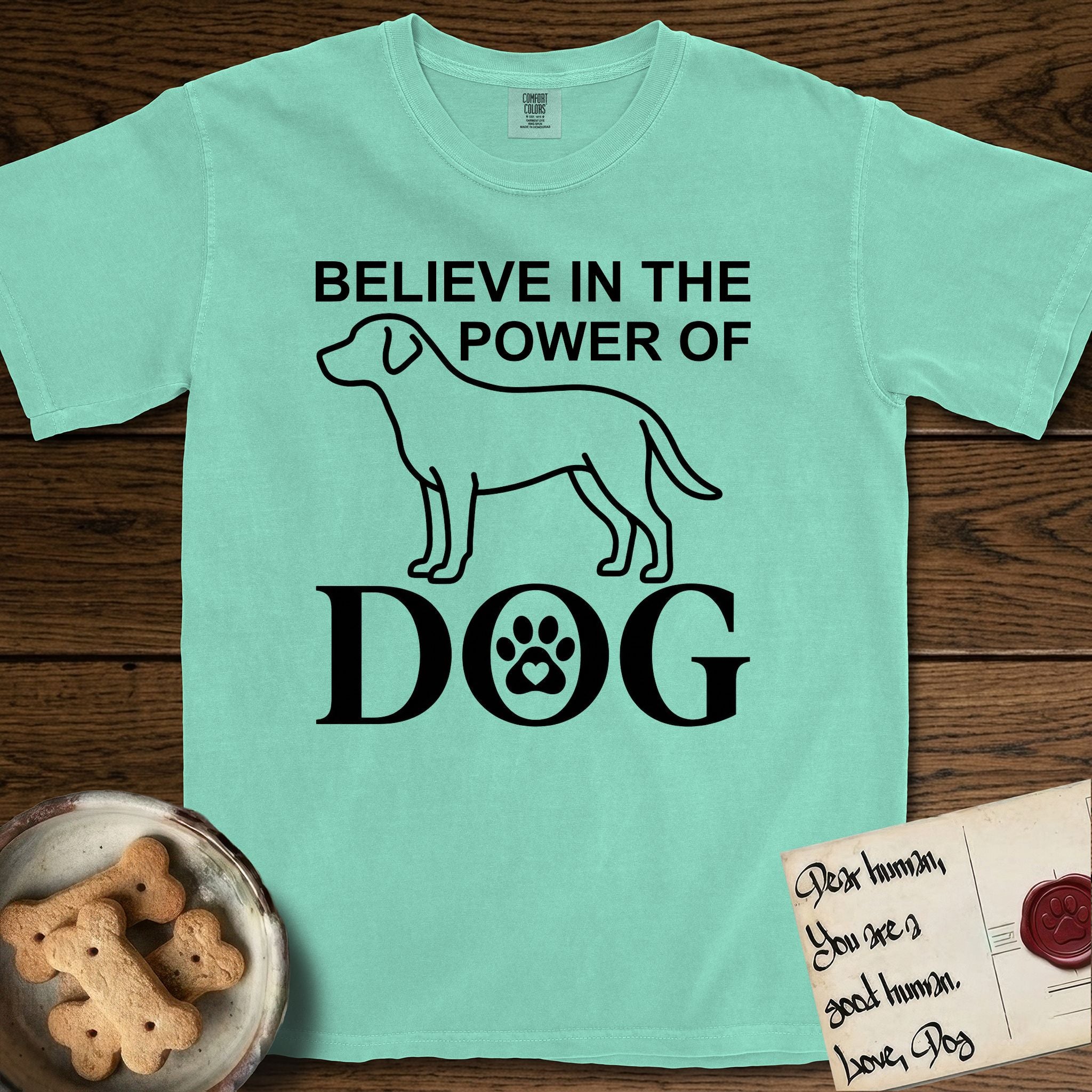 Believe in the Power of Dog Labrador T-Shirt flat lay in Island Reef, featuring stark minimalist single-line art of a Labrador with bold stacked "Believe in the Power of Dog" type and a paw-print heart in the O.