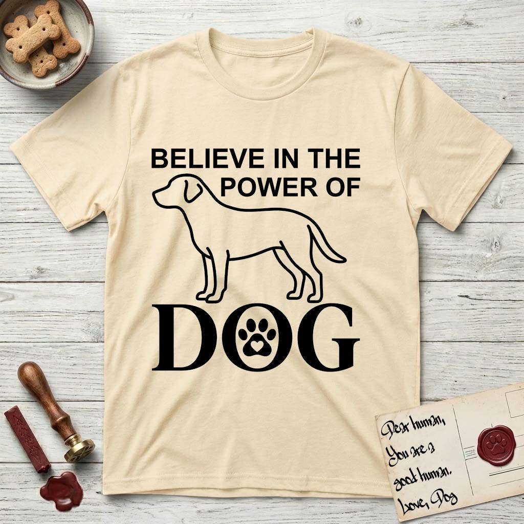 Believe in the Power of Dog Labrador T-Shirt flat lay in Natural, featuring stark minimalist single-line art of a Labrador with bold stacked "Believe in the Power of Dog" type and a paw-print heart in the O.