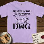 Believe in the Power of Dog Labrador T-Shirt flat lay in Orchid, featuring stark minimalist single-line art of a Labrador with bold stacked "Believe in the Power of Dog" type and a paw-print heart in the O.