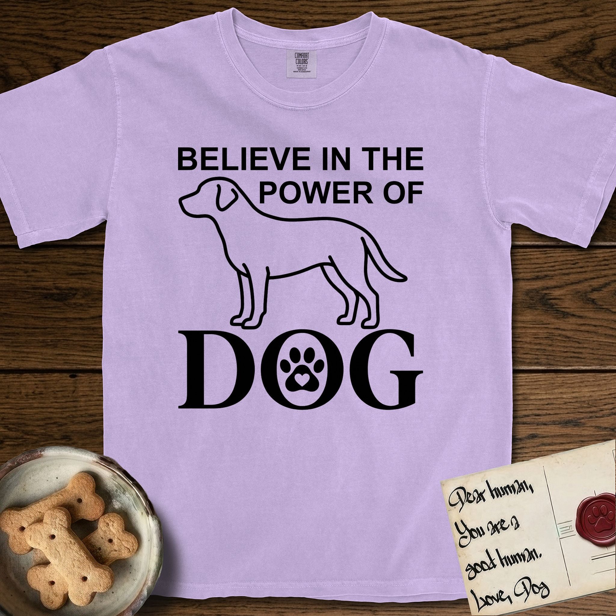 Believe in the Power of Dog Labrador T-Shirt flat lay in Orchid, featuring stark minimalist single-line art of a Labrador with bold stacked "Believe in the Power of Dog" type and a paw-print heart in the O.