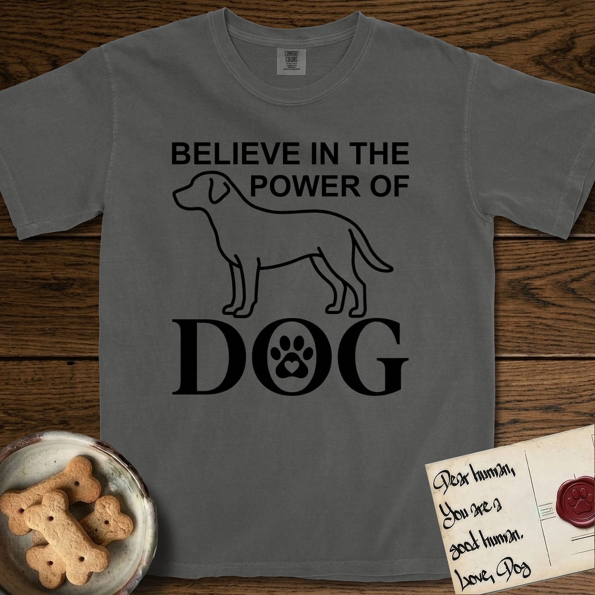 Believe in the Power of Dog Labrador T-Shirt flat lay in Pepper, featuring stark minimalist single-line art of a Labrador with bold stacked "Believe in the Power of Dog" type and a paw-print heart in the O.