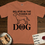 Believe in the Power of Dog Labrador T-Shirt flat lay in Yam, featuring stark minimalist single-line art of a Labrador with bold stacked "Believe in the Power of Dog" type and a paw-print heart in the O.