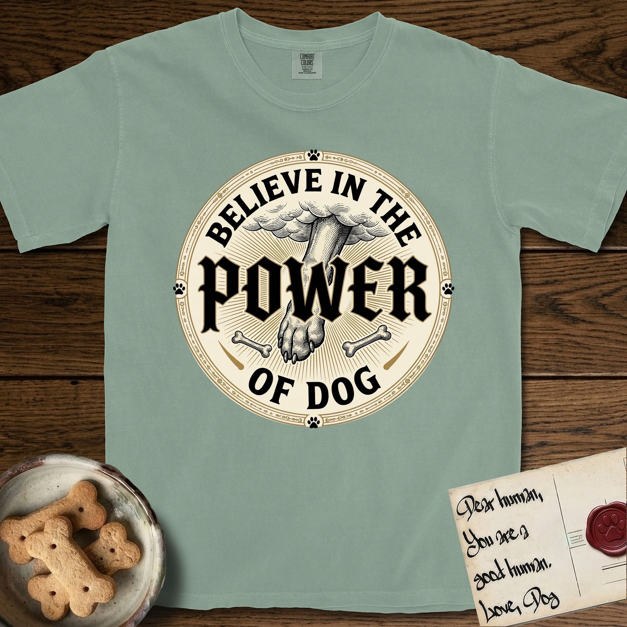 Believe in the Power of Dog Paw T-Shirt flat lay in Bay, featuring a vintage engraving medallion of a Dog paw and a human hand meeting over crossed bones in a sunburst.