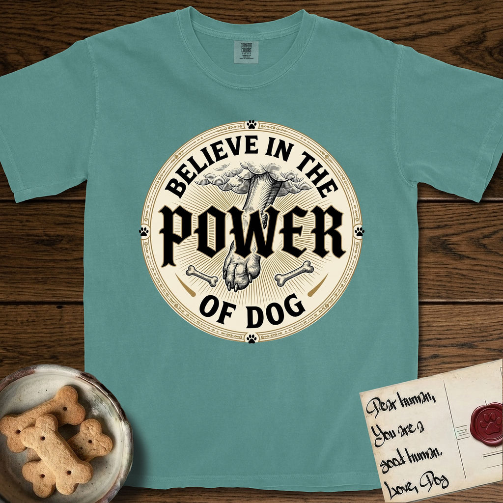 Believe in the Power of Dog Paw T-Shirt flat lay in Blue Spruce, featuring a vintage engraving medallion of a Dog paw and a human hand meeting over crossed bones in a sunburst.