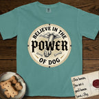 Believe in the Power of Dog Paw T-Shirt flat lay in Blue Spruce, featuring a vintage engraving medallion of a Dog paw and a human hand meeting over crossed bones in a sunburst.