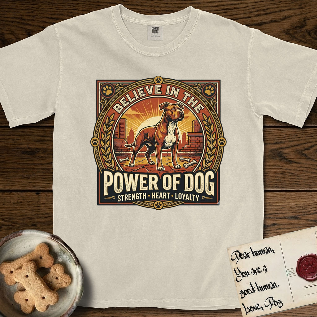Believe in the Power of Dog Pitbull T-Shirt flat lay in Ivory, featuring a vintage urban badge with a brick-red Pitbull, a city skyline, a radiating sun, and the words Strength, Heart, Loyalty.