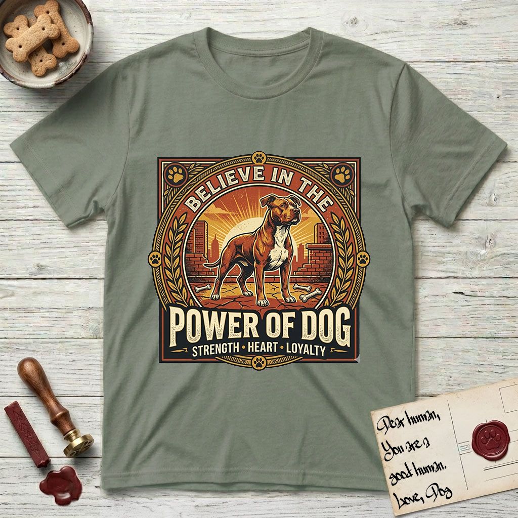 Believe in the Power of Dog Pitbull Cityscape T-Shirt flat lay in Sage, featuring a vintage urban badge with a brick-red Pitbull, a city skyline, a radiating sun, and the words Strength, Heart, Loyalty.