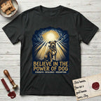 Believe in the Power of Dog Pitbull Clouds T-Shirt flat lay in Black, featuring a devotional badge with a seated Pitbull, parting clouds and radiating light, and the words Strength, Resilience, Redemption.