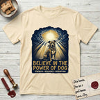 Believe in the Power of Dog Pitbull Clouds T-Shirt flat lay in Natural, featuring a devotional badge with a seated Pitbull, parting clouds and radiating light, and the words Strength, Resilience, Redemption.