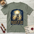 Believe in the Power of Dog Pitbull Clouds T-Shirt flat lay in Sage, featuring a devotional badge with a seated Pitbull, parting clouds and radiating light, and the words Strength, Resilience, Redemption.