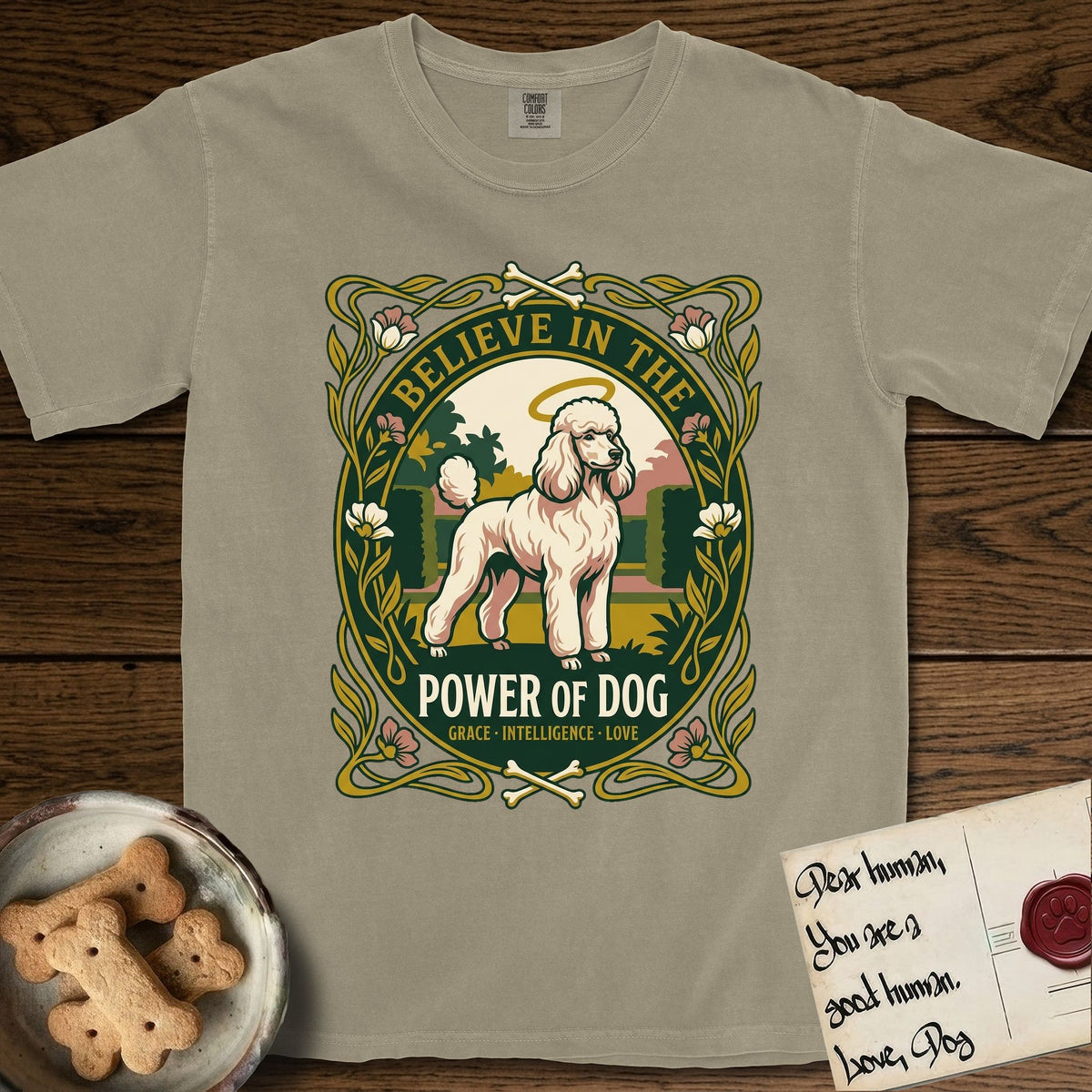 Believe in the Power of Dog Poodle T-Shirt flat lay in Khaki, featuring an Art Nouveau floral badge with a haloed Poodle in a garden park scene and the words Grace, Intelligence, Love.