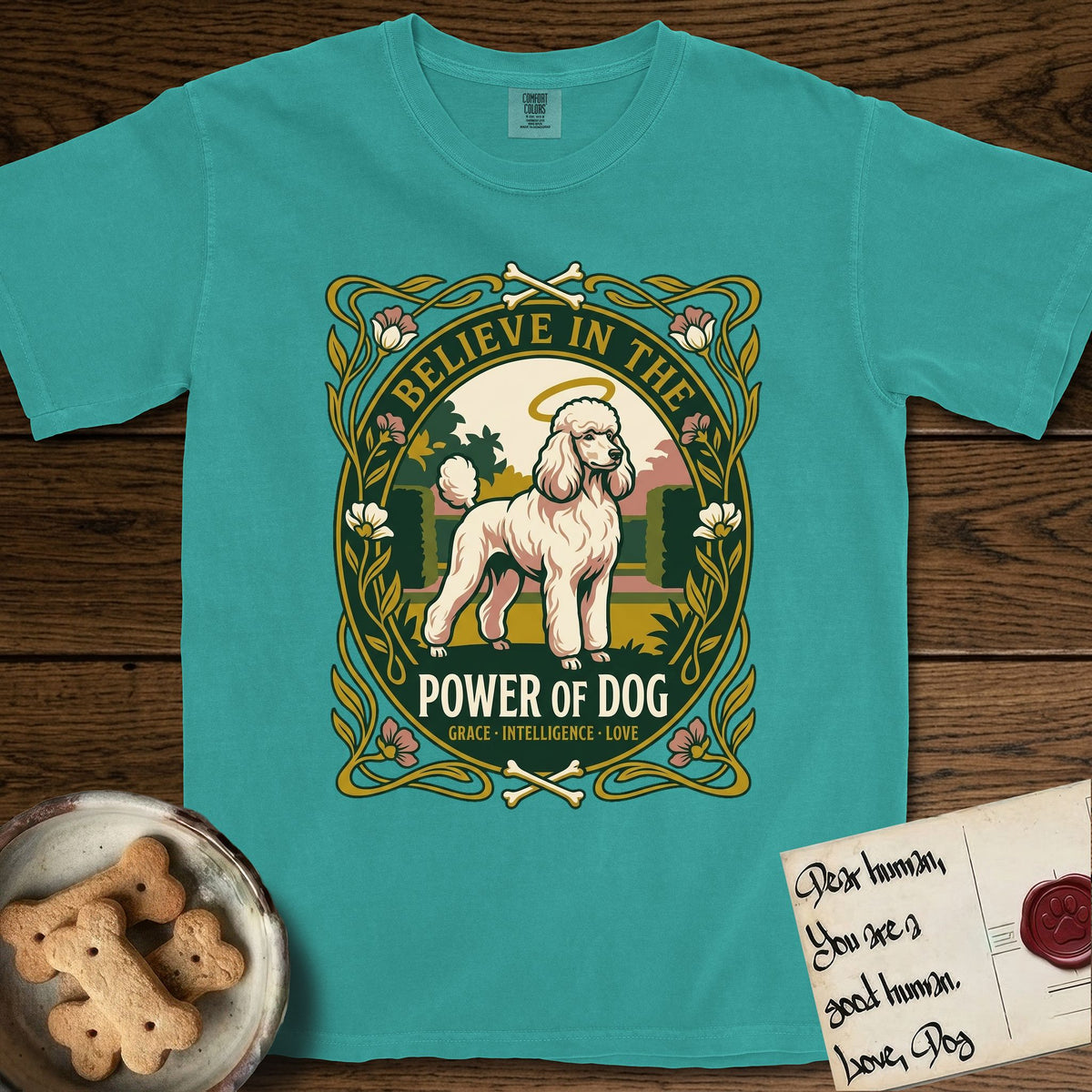 Believe in the Power of Dog Poodle T-Shirt flat lay in Seafoam, featuring an Art Nouveau floral badge with a haloed Poodle in a garden park scene and the words Grace, Intelligence, Love.