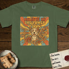 Believe in the Power of Dog Rescue Mutt T-Shirt flat lay in Moss, featuring a retro 1970s groovy poster of a grinning rescue mutt with a radiating sunburst and swirling florals.