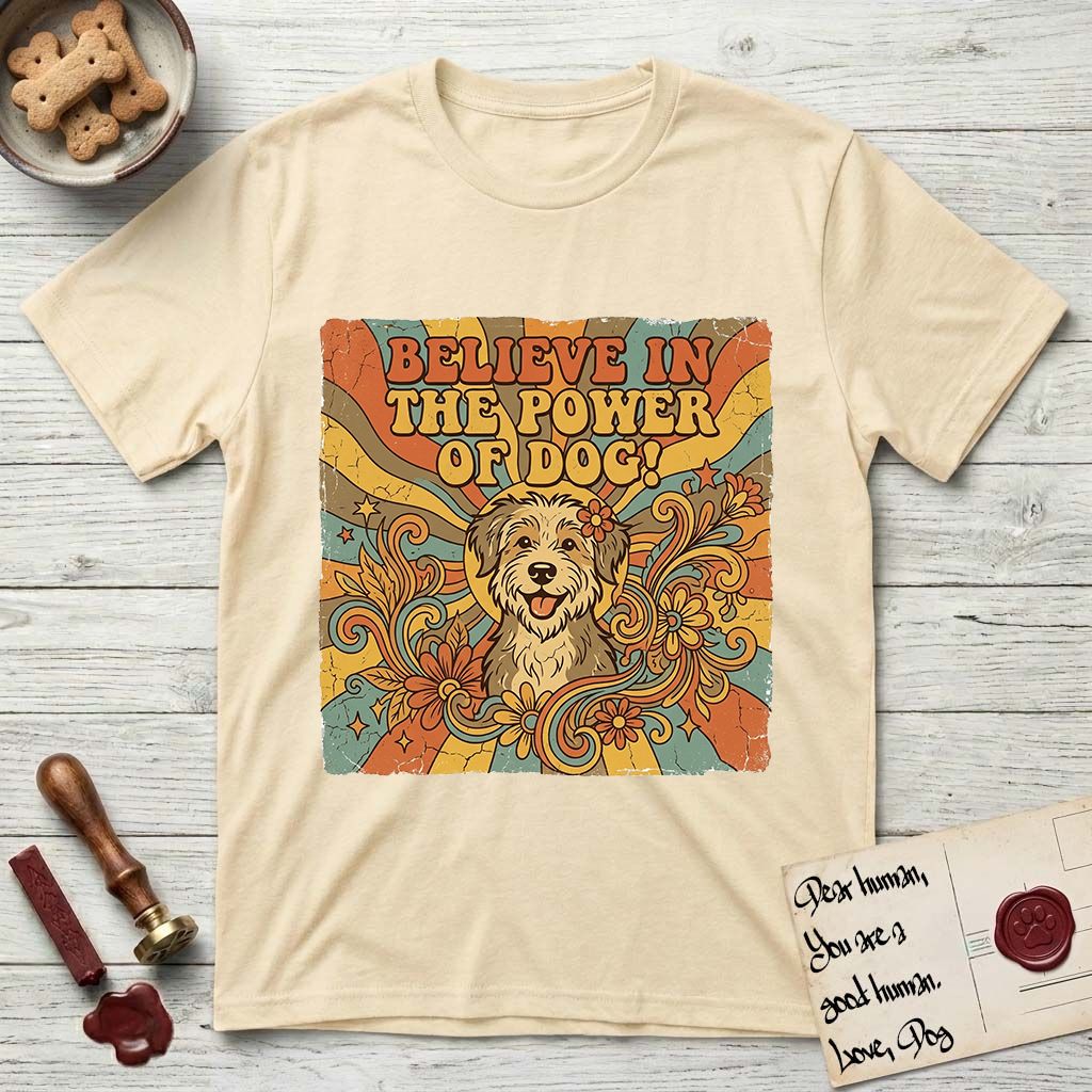 Believe in the Power of Dog Rescue Mutt T-Shirt flat lay in Natural, featuring a retro 1970s groovy poster of a grinning rescue mutt with a radiating sunburst and swirling florals.