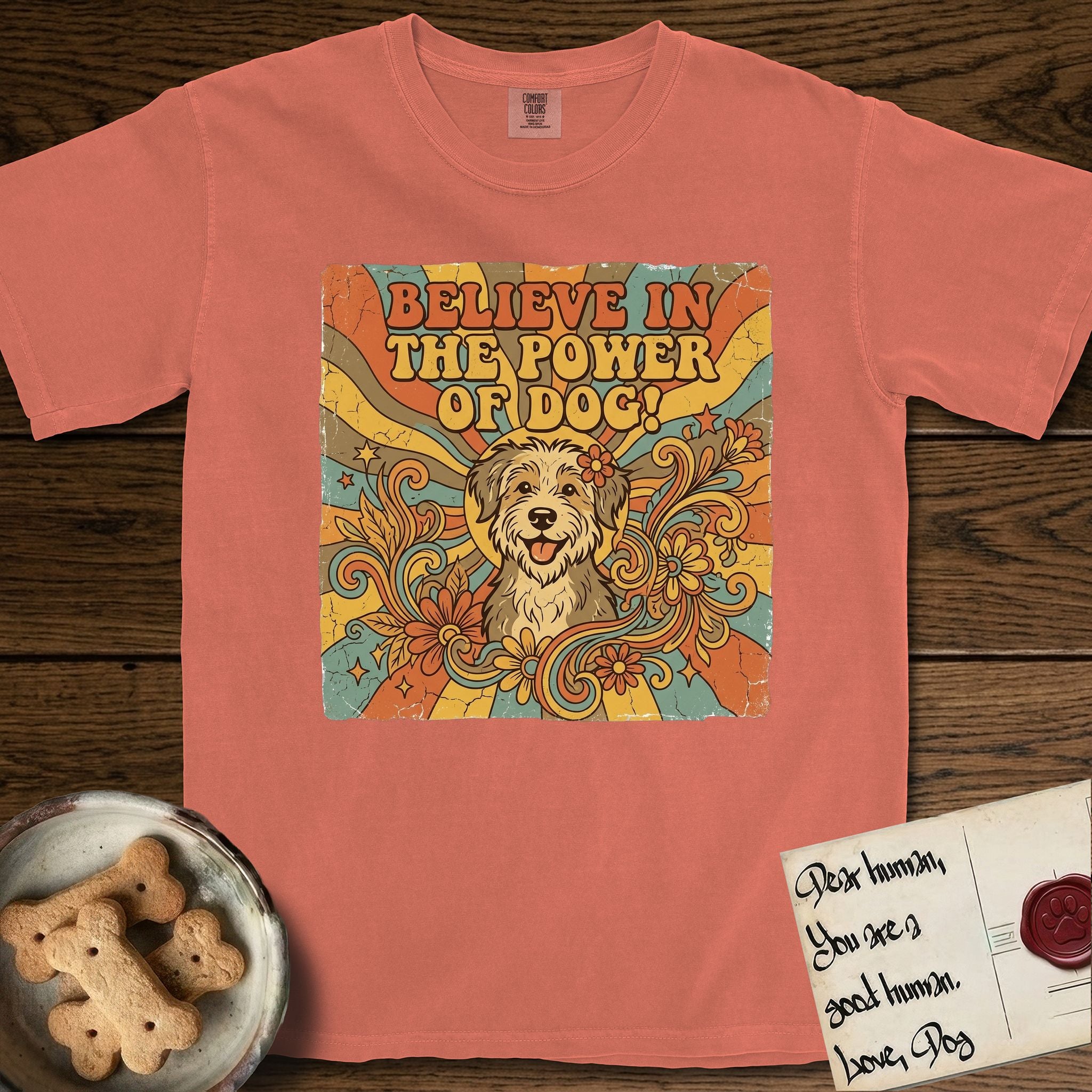 Believe in the Power of Dog Rescue Mutt T-Shirt flat lay in Terracotta, featuring a retro 1970s groovy poster of a grinning rescue mutt with a radiating sunburst and swirling florals.