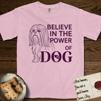 Believe in the Power of Dog Shih Tzu T-Shirt flat lay in Blossom, featuring a clean single-color line drawing of a long-coated Shih Tzu beside the stacked words Believe in the Power of Dog with a paw print pressed into the O.