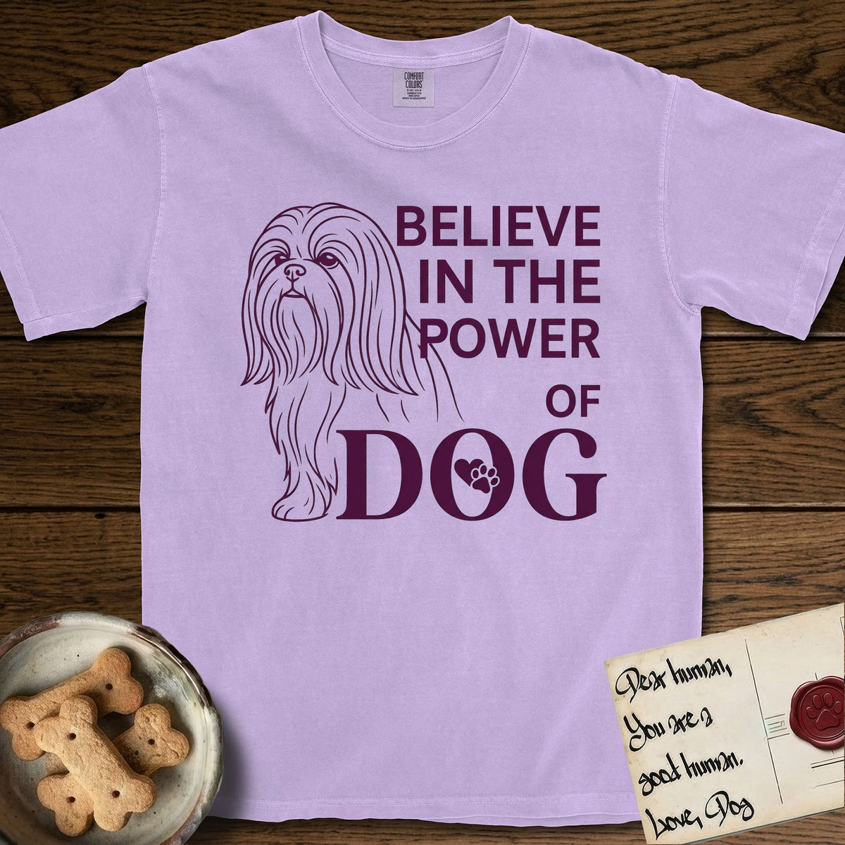 Believe in the Power of Dog Shih Tzu T-Shirt flat lay in Orchid, featuring a clean single-color line drawing of a long-coated Shih Tzu beside the stacked words Believe in the Power of Dog with a paw print pressed into the O.
