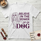 Believe in the Power of Dog Shih Tzu Line Drawing T-Shirt flat lay in White, featuring a clean single-color line drawing of a long-coated Shih Tzu beside the stacked words Believe in the Power of Dog with a paw print pressed into the O.