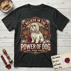Believe in the Power of Dog Shih Tzu Throne T-Shirt flat lay in Black, featuring an ornate dark badge with a Shih Tzu seated on a throne among chrysanthemums, lotus blossoms and mountain landscapes, and the words Grace, Wisdom, Devotion.