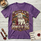 Believe in the Power of Dog Shih Tzu Throne T-Shirt flat lay in Heather Purple, featuring an ornate dark badge with a Shih Tzu seated on a throne among chrysanthemums, lotus blossoms and mountain landscapes, and the words Grace, Wisdom, Devotion.