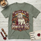 Believe in the Power of Dog Shih Tzu Throne T-Shirt flat lay in Sage, featuring an ornate dark badge with a Shih Tzu seated on a throne among chrysanthemums, lotus blossoms and mountain landscapes, and the words Grace, Wisdom, Devotion.